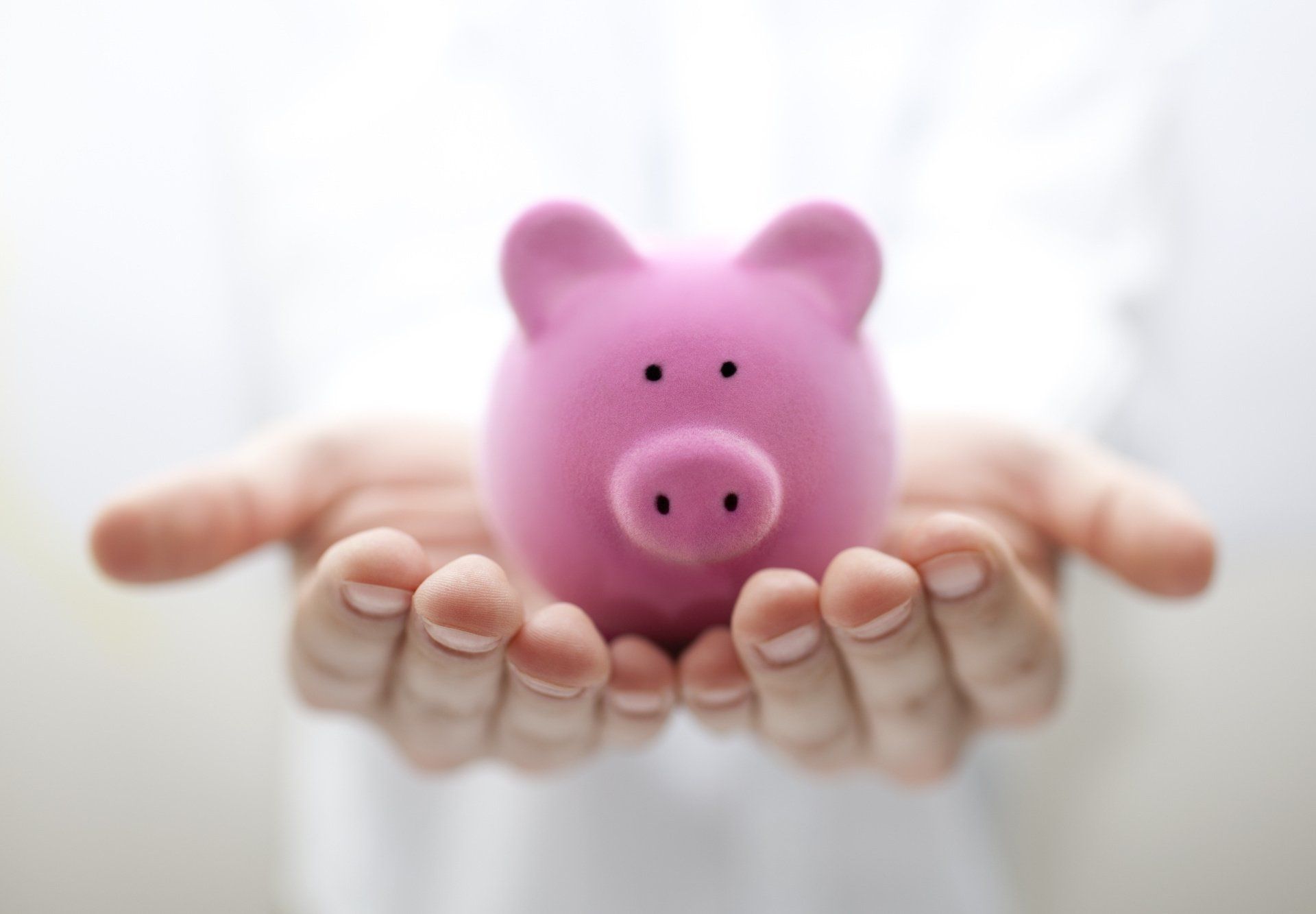 Pink piggy bank held in a woman's hands.