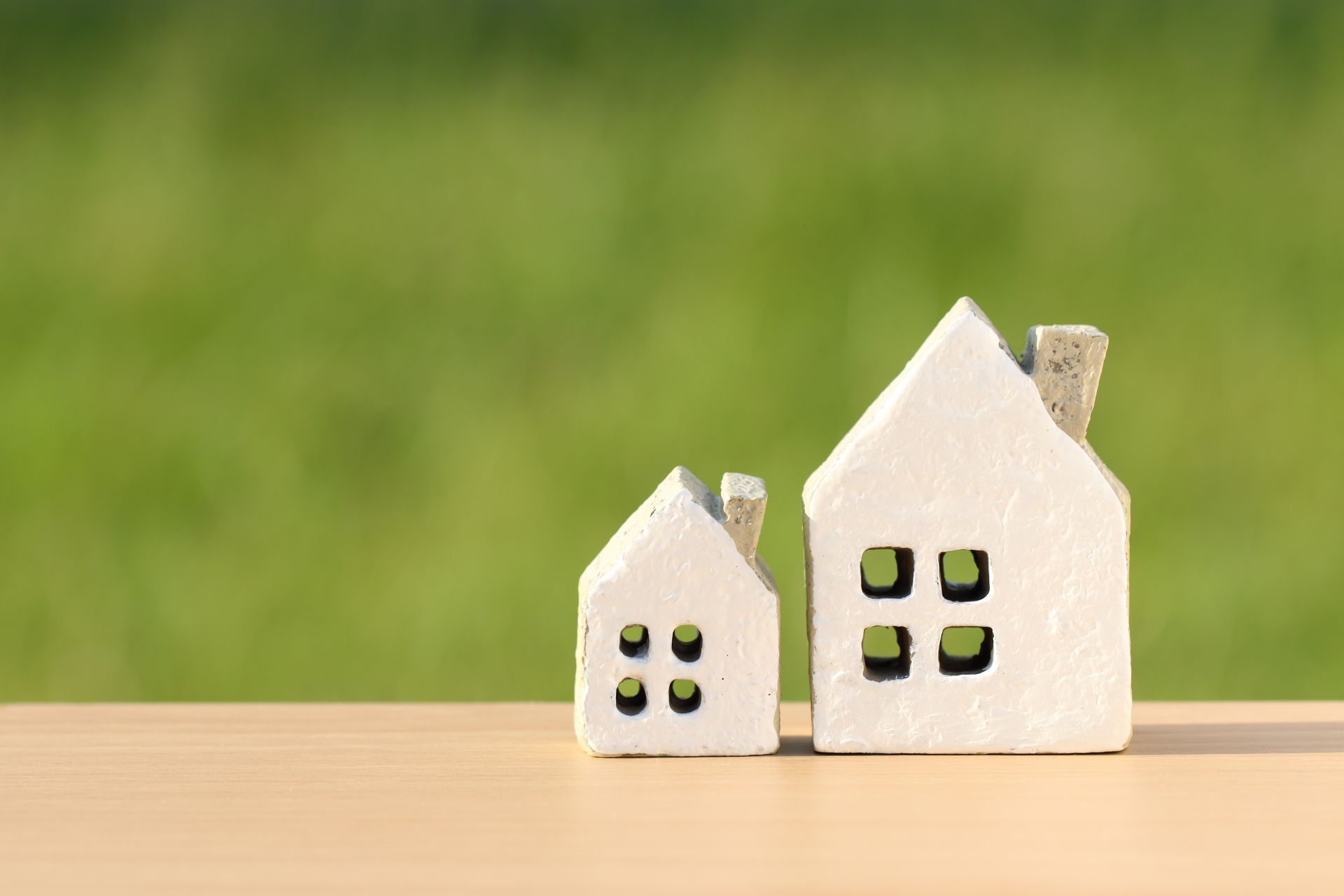 Clay figures of a small and large house sitting on a table.