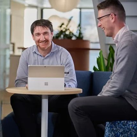 Gavin Mitchell, partner, and Jade Giang, manager, are walking down a hallway and talking together in an office environment.