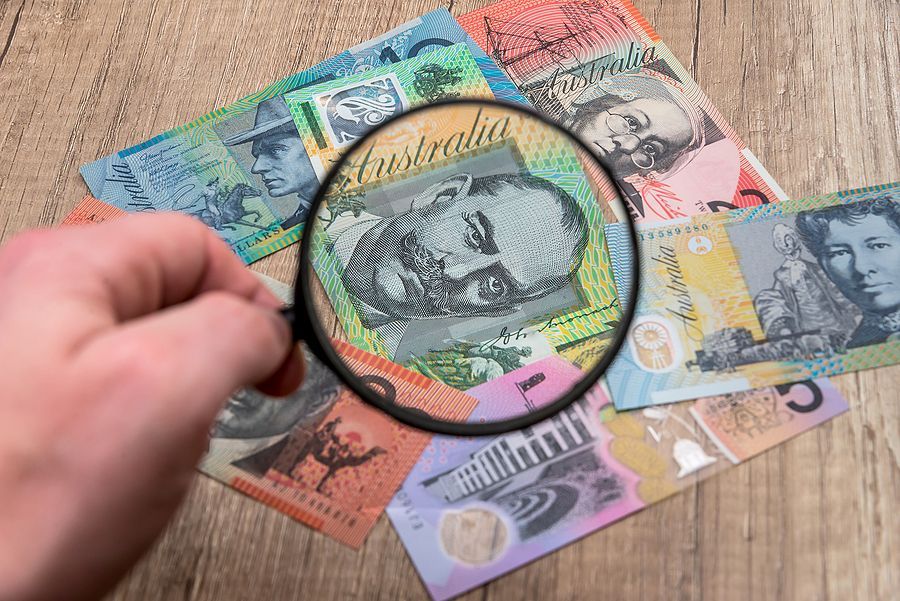 Australian notes under a magnifying glass in hand