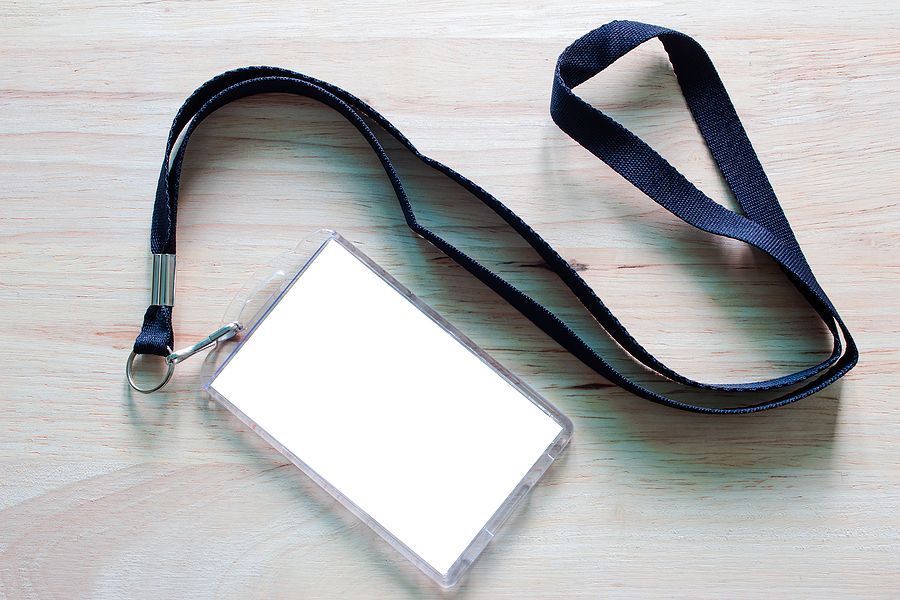 Blank badge mockup isolated on wooden. Lanyard and badge. Plastic badge. Template for presentation of their design. Plain empty name tag mock up hanging on neck with string.