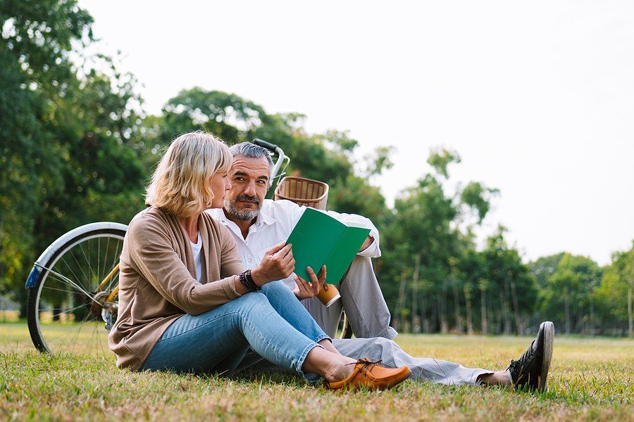 Elderly Couple Relaxing And Sitting At The Park Reading The Retirement Plan To Discussing