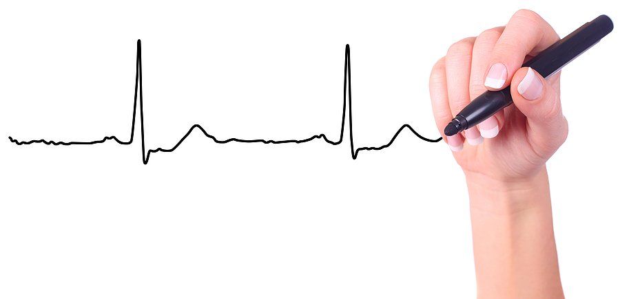 A hand holding a black marker which has drawn a heart beat line.