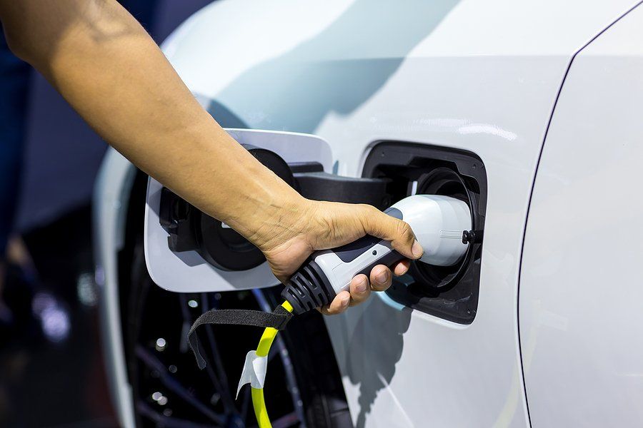 A person placing an electric car charger into their car.