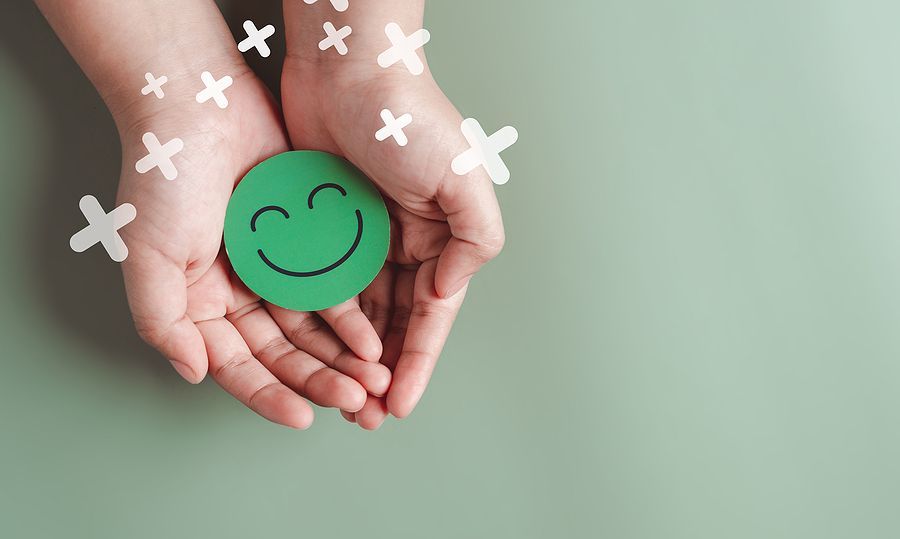 Hands holding green happy smile face, good feedback rating, positive customer review, experience, satisfaction survey, smiley mental health, child wellness, world mental health day on green background