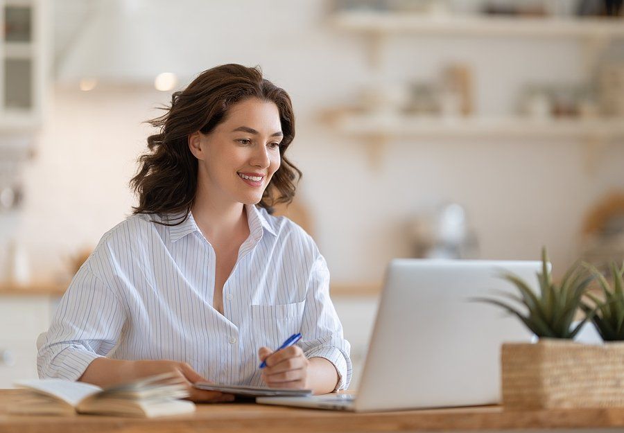 Happy young woman working online, watching webinar, podcast on laptop, having remote conversation at home.