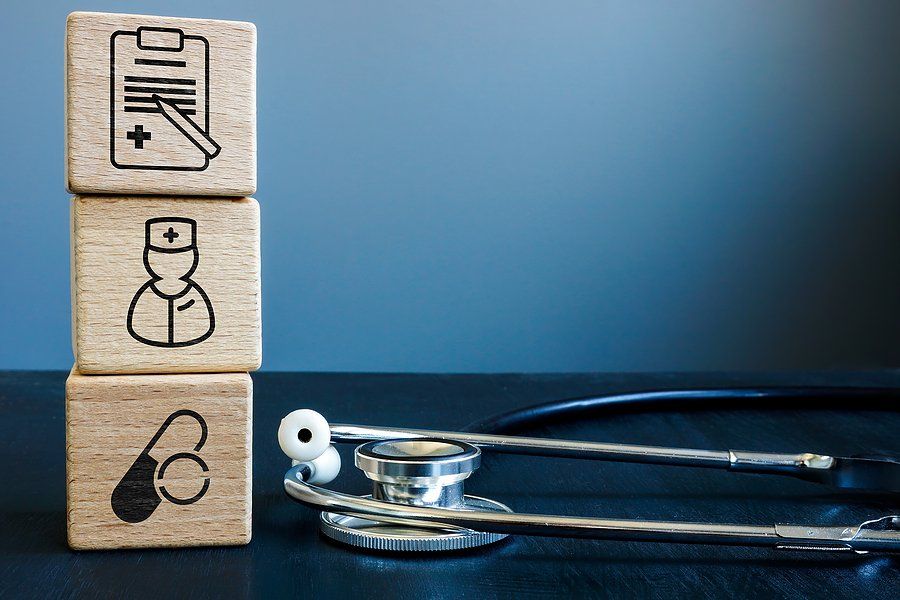 Wooden blocks with icons, medical records, nurse and pills. A stethoscope is lying next to it.