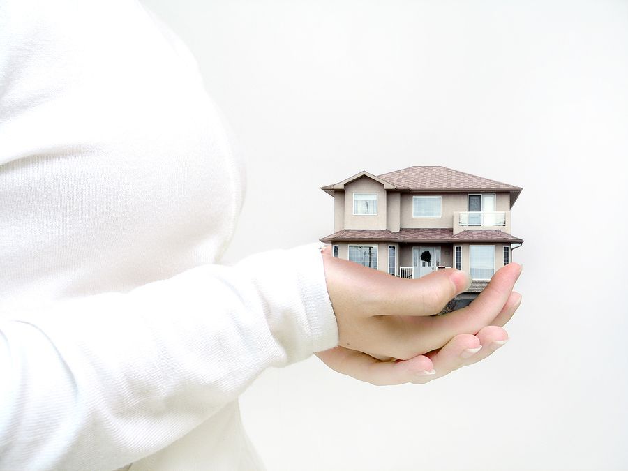 A woman in a white top is holding a miniature house.