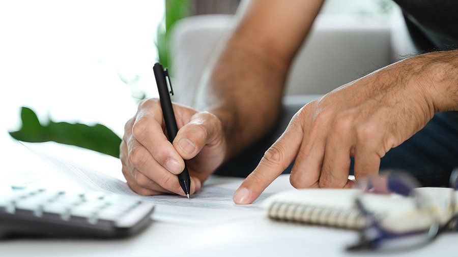 Man calculating annual tax with a pen in his hand.