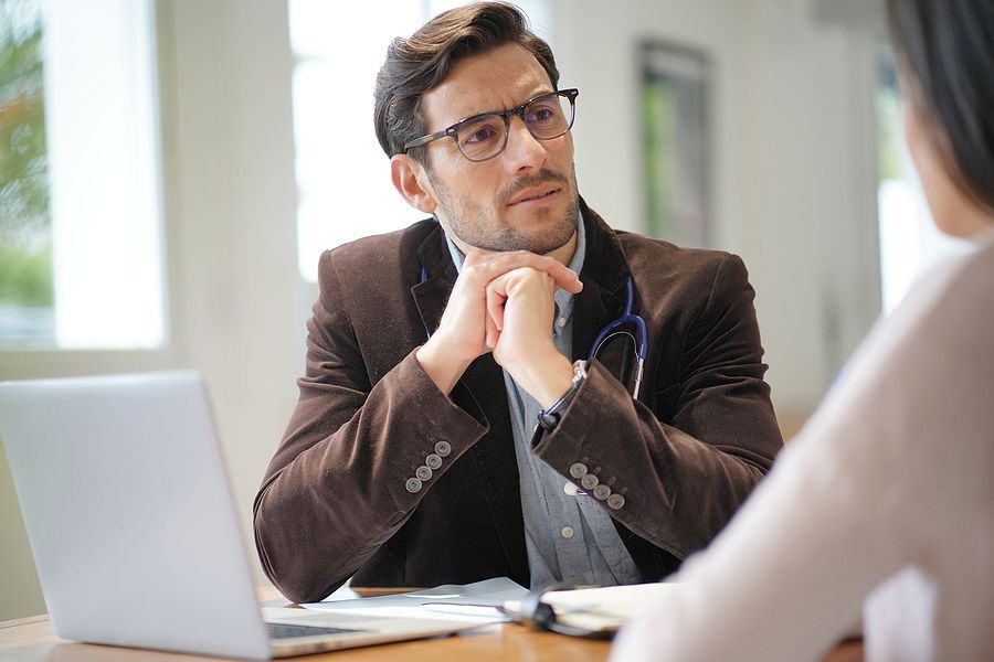 Modern young doctor speaking to patient in office