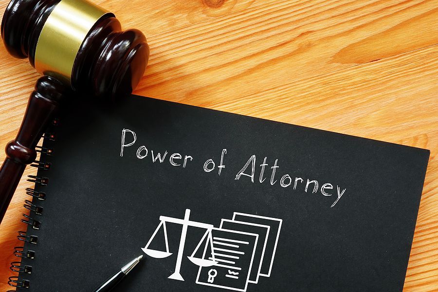 Power of Attorney is shown using a text book and a gravel next to it on a laying on a table.