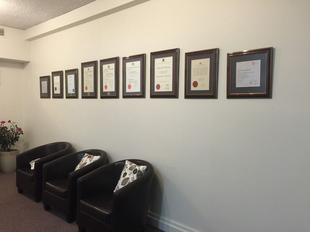 A Row of Framed Certificates on a White Wall Above Black Leather Chairs — Hannaway Lawyers in Port Macquarie, NSW