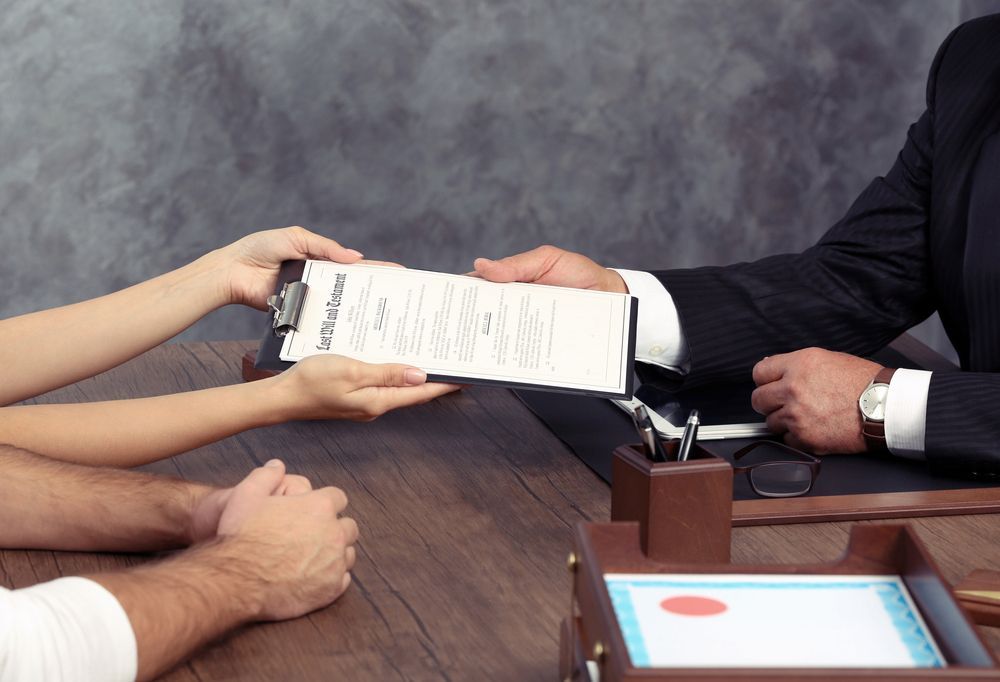 Person in Suit Hands Last Will Testament Documents to a Person — Hannaway Lawyers in Port Macquarie, NSW
