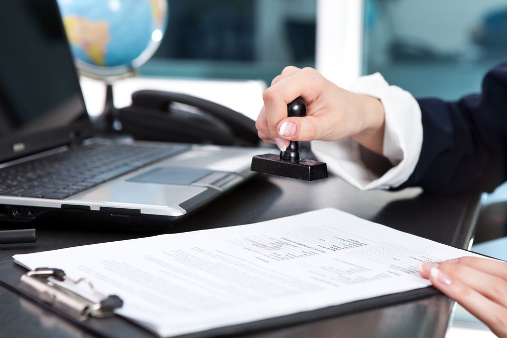 Woman in Suit Stamping Documents on a Clipboard at a Desk — Hannaway Lawyers in Port Macquarie, NSW