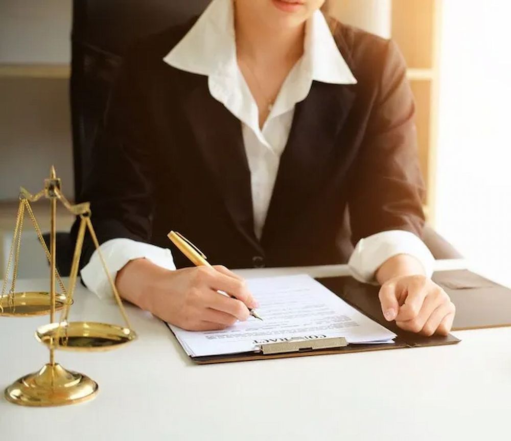 Woman in Suit, Writing on a Document at a Desk — Hannaway Lawyers in Port Macquarie, NSW