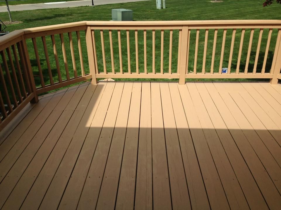 A wooden deck with a wooden railing and grass in the background
