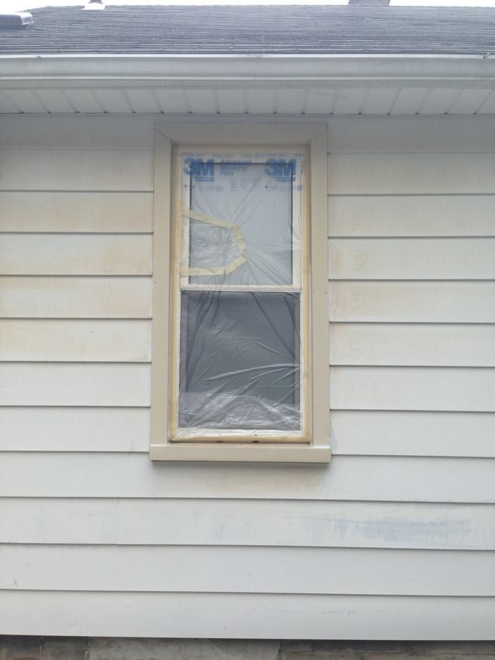A window on the side of a house is covered in plastic.