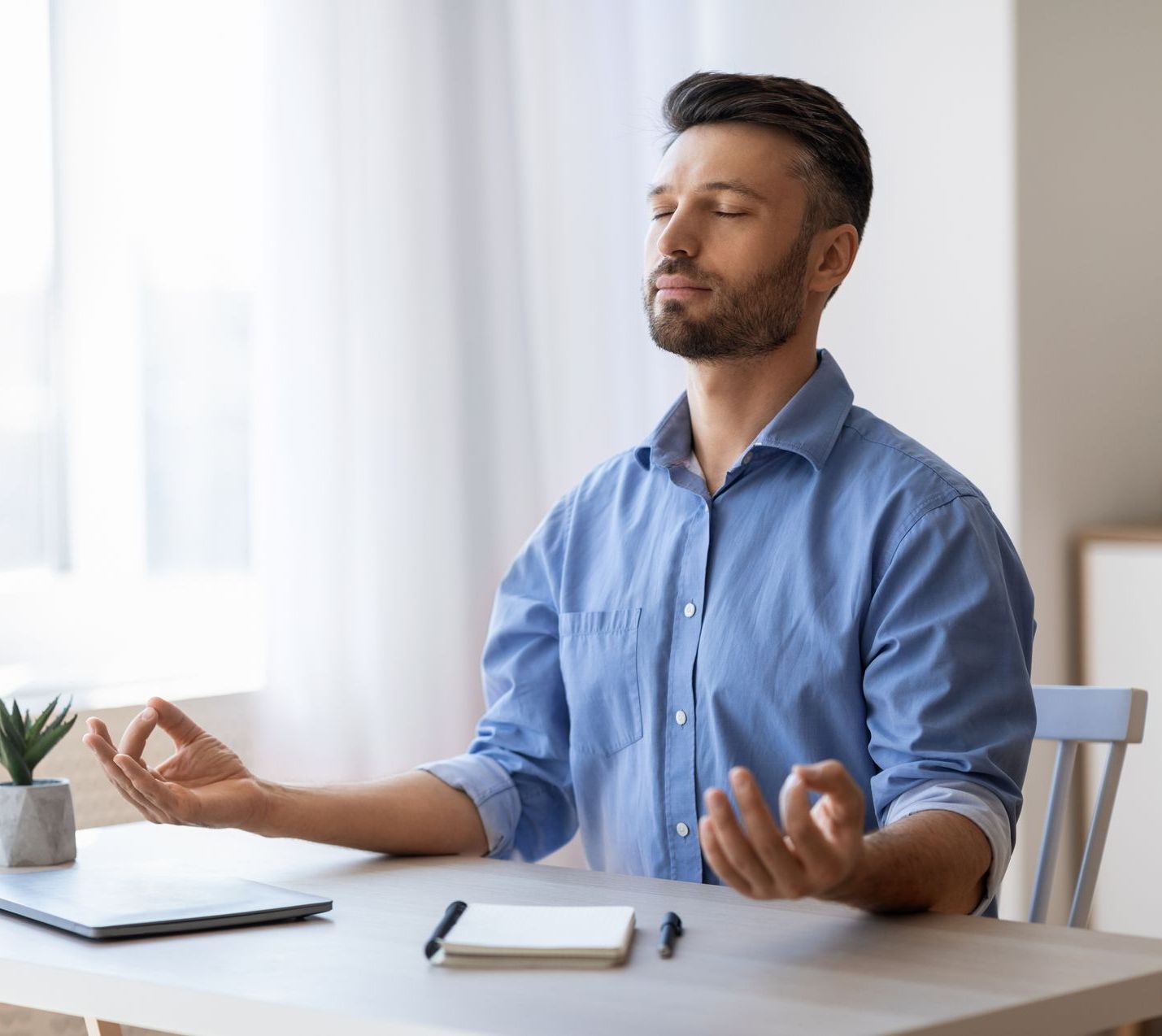 a man is sitting at a table meditating with his eyes closed .