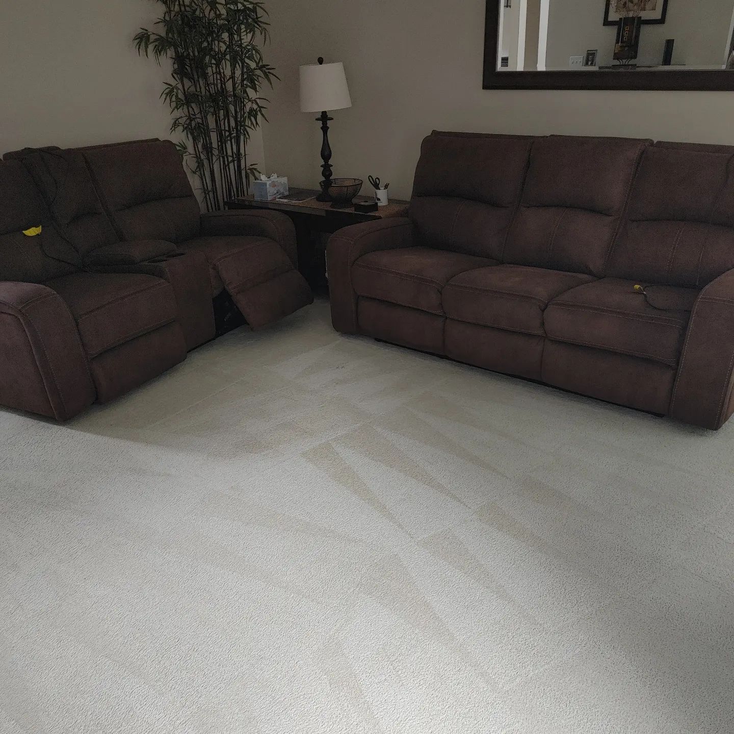 A living room with two brown couches and a white carpet.