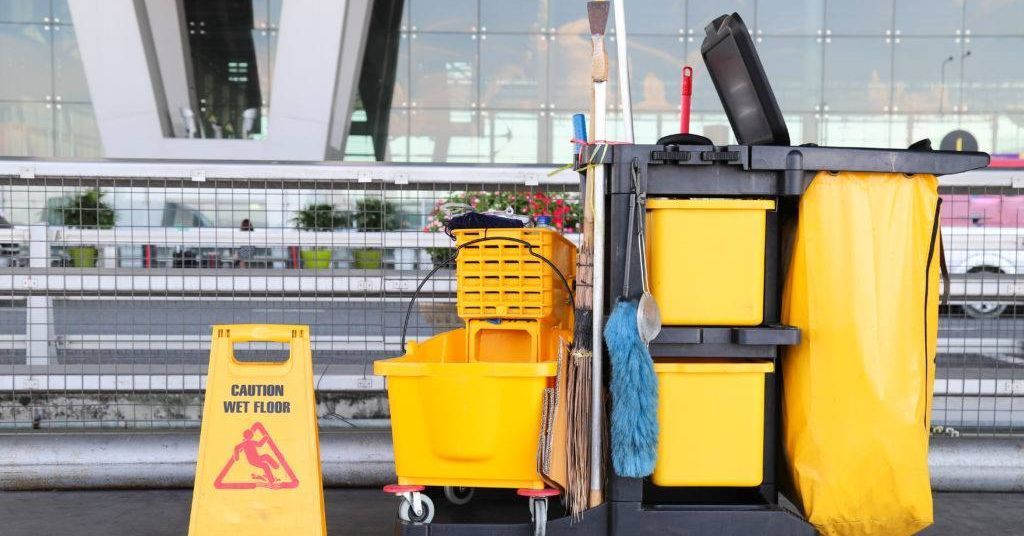 A yellow caution sign is next to a cleaning cart.