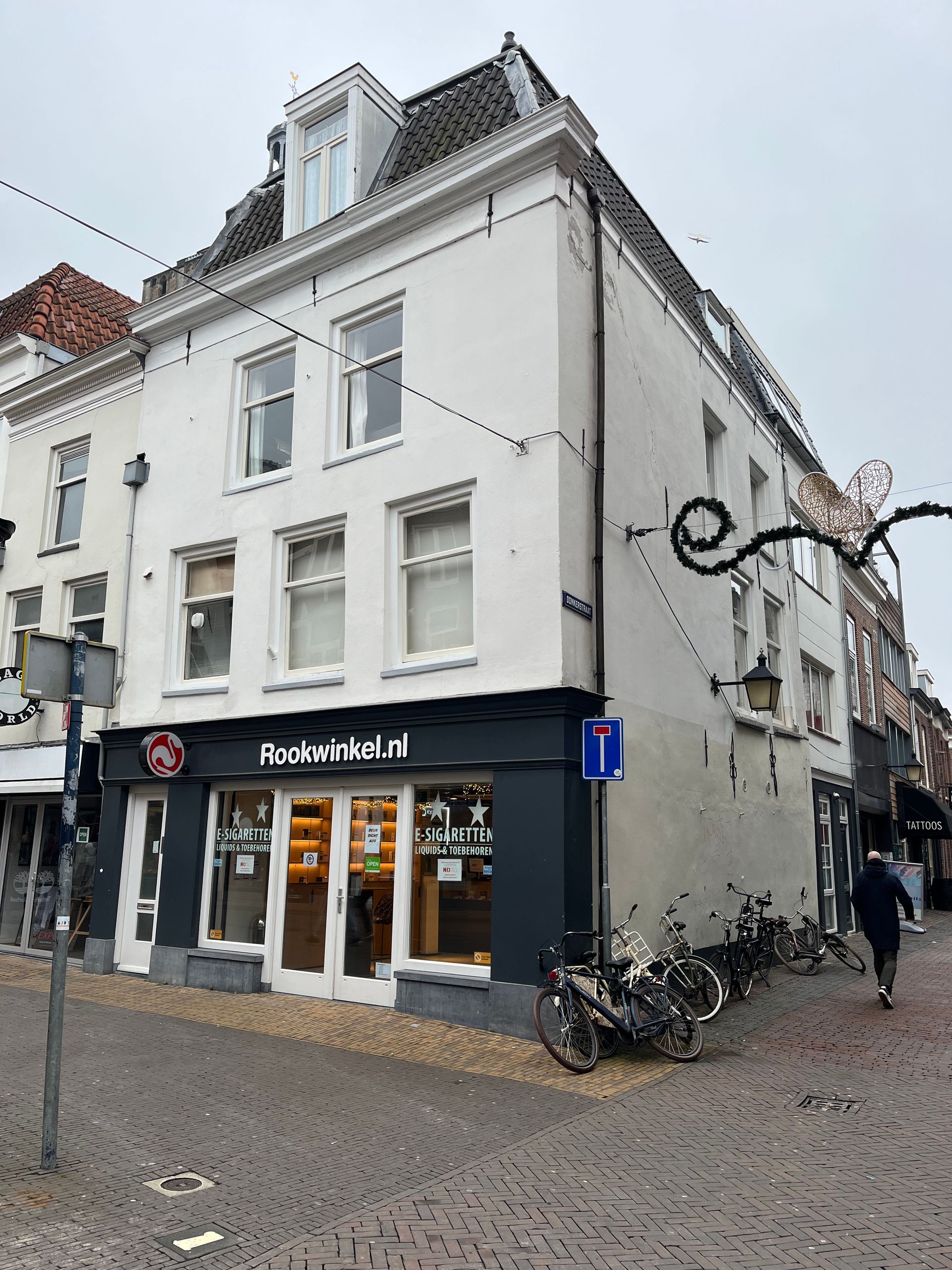 Buitenaanzicht van een wit gebouw met een Broodjes & Zo-winkel op de begane grond. Fietsen staan ​​buiten geparkeerd.