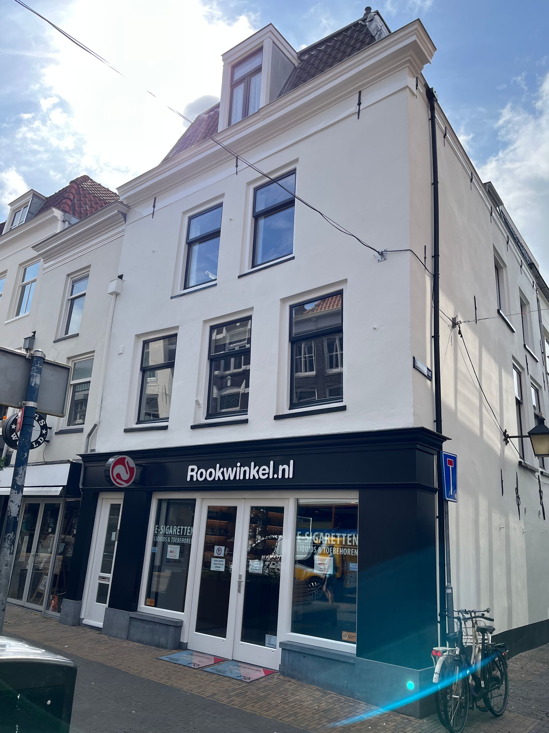 Wit gebouw met winkelpui, ramen en schuin dak; bord 'Boekwinkel.nl' boven de ingang.