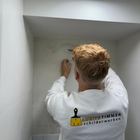 Een persoon in een wit sweatshirt werkt aan een muur in een ingebouwde plank.