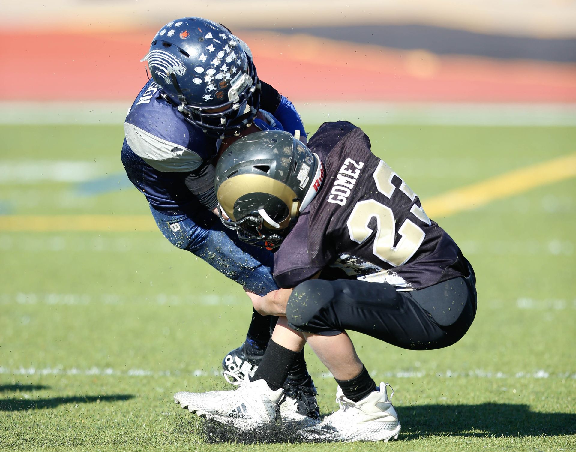Football player in silver uniform runs with ball on a green field.