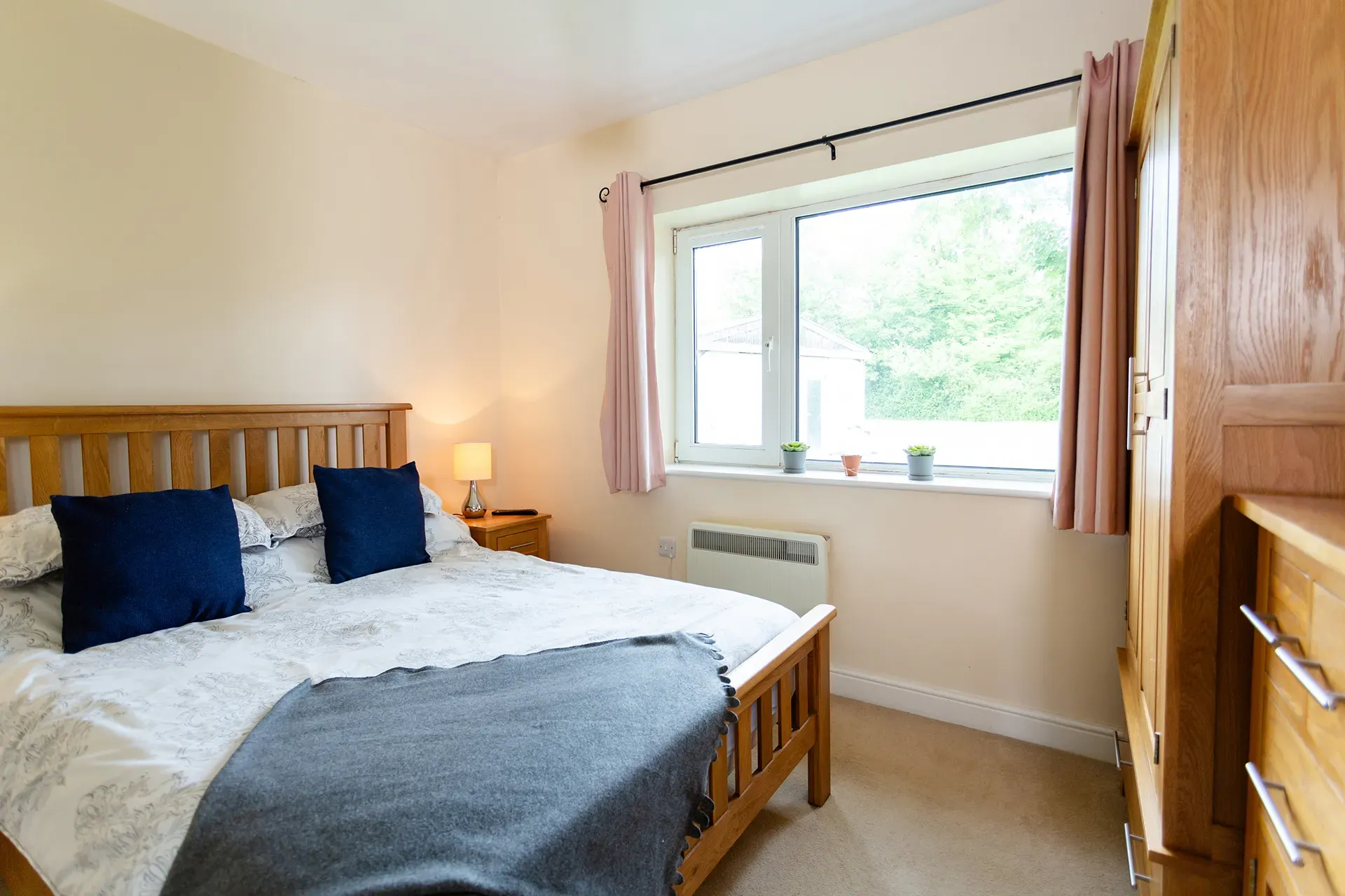 A bedroom with a bed , dresser , and window.