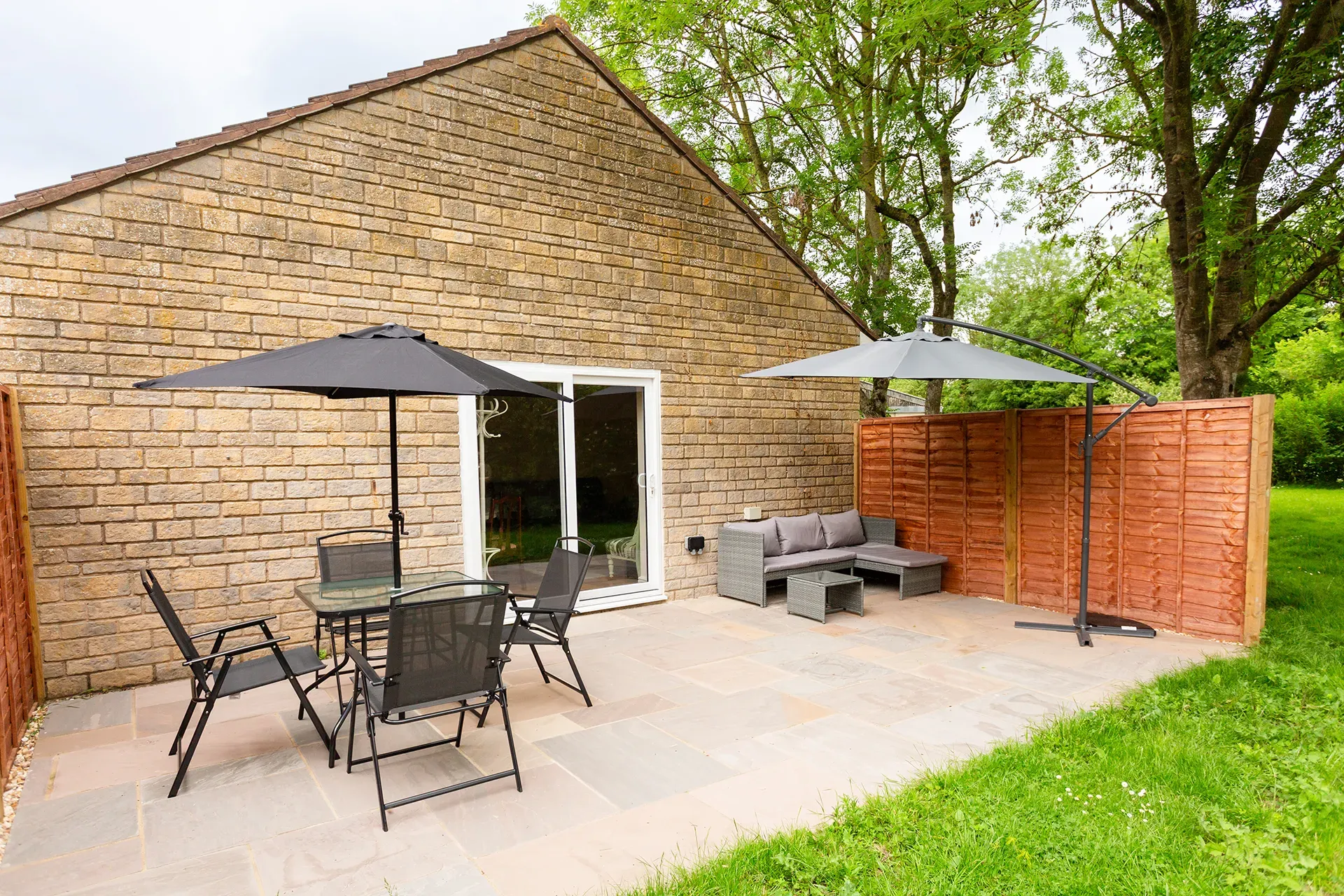 A patio with a table and chairs and umbrellas in front of a brick building.