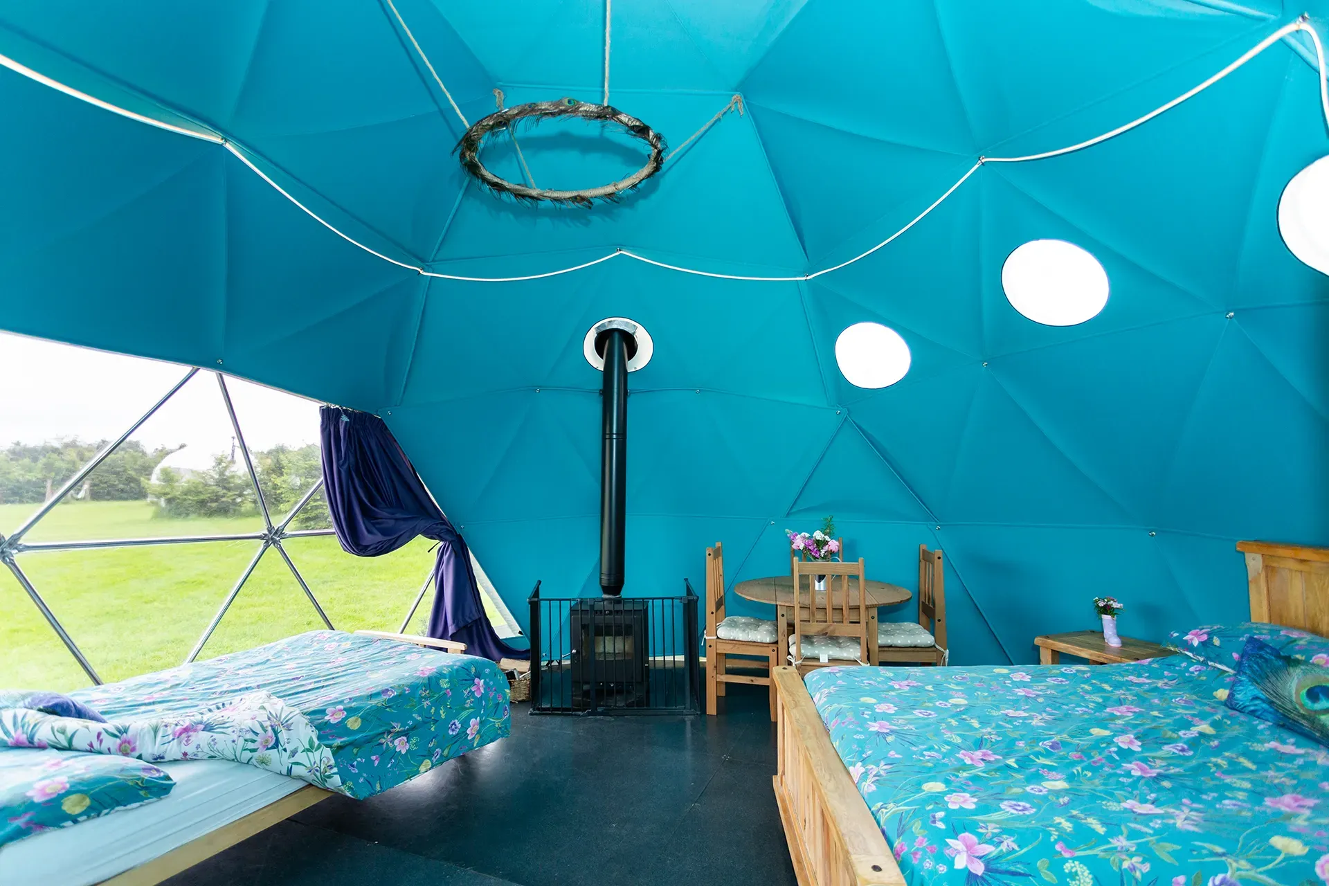 A blue dome with two beds , a table and chairs inside of it.