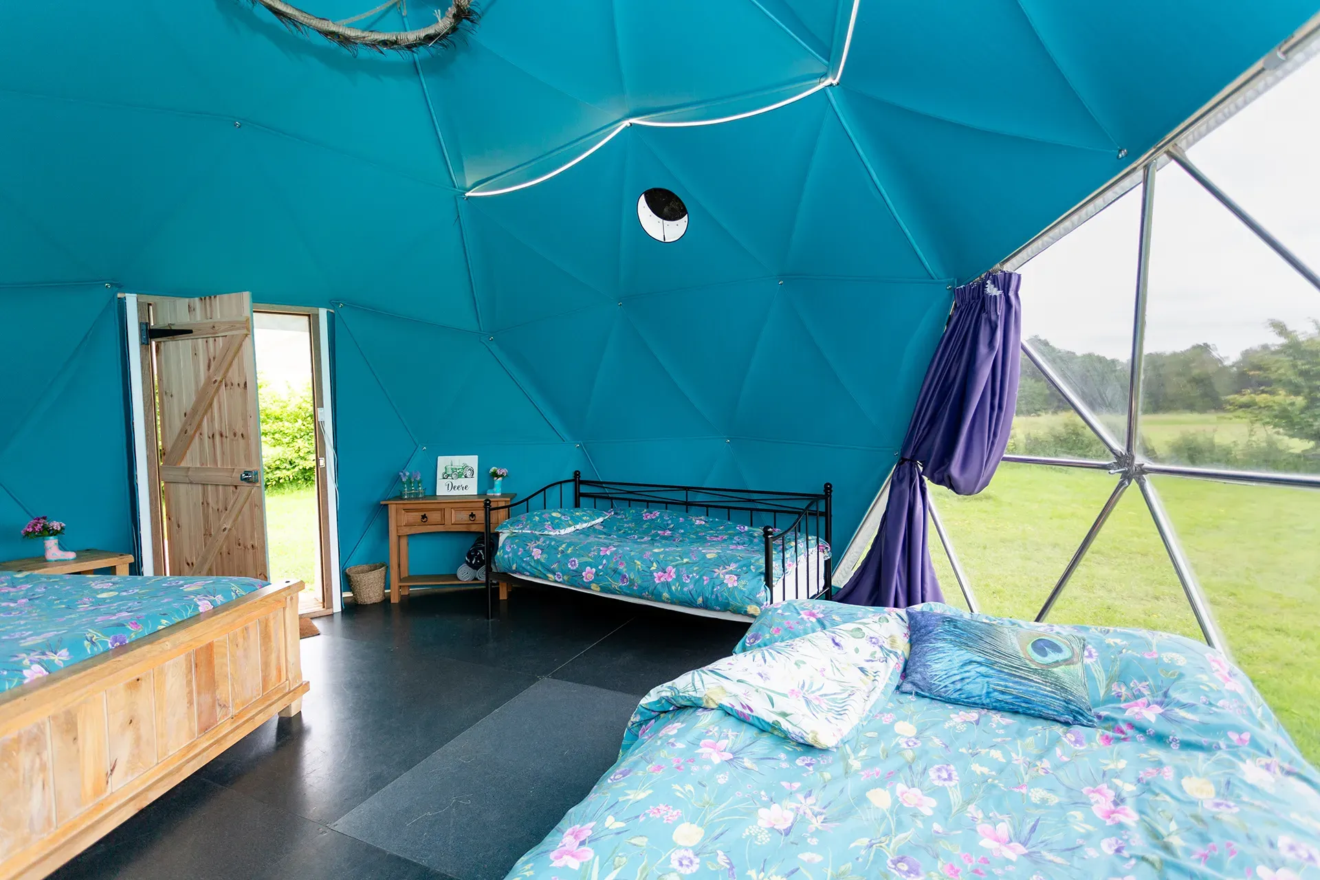 There are three beds in a dome with blue walls.