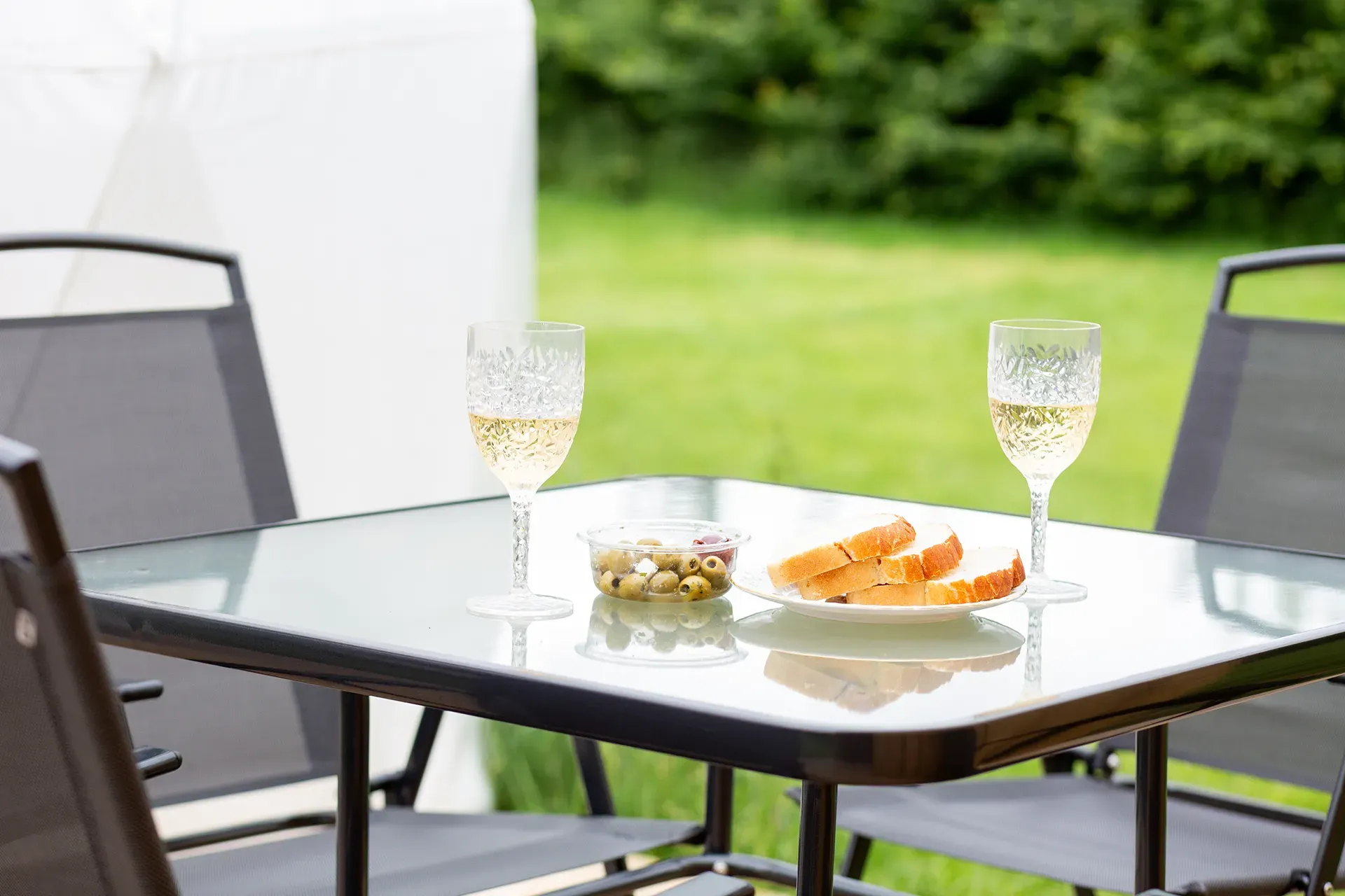 A table with a plate of food and two glasses of wine on it.