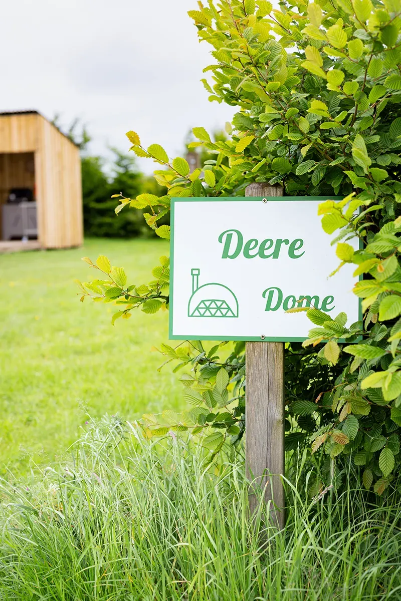 A sign in the grass says deere dome.