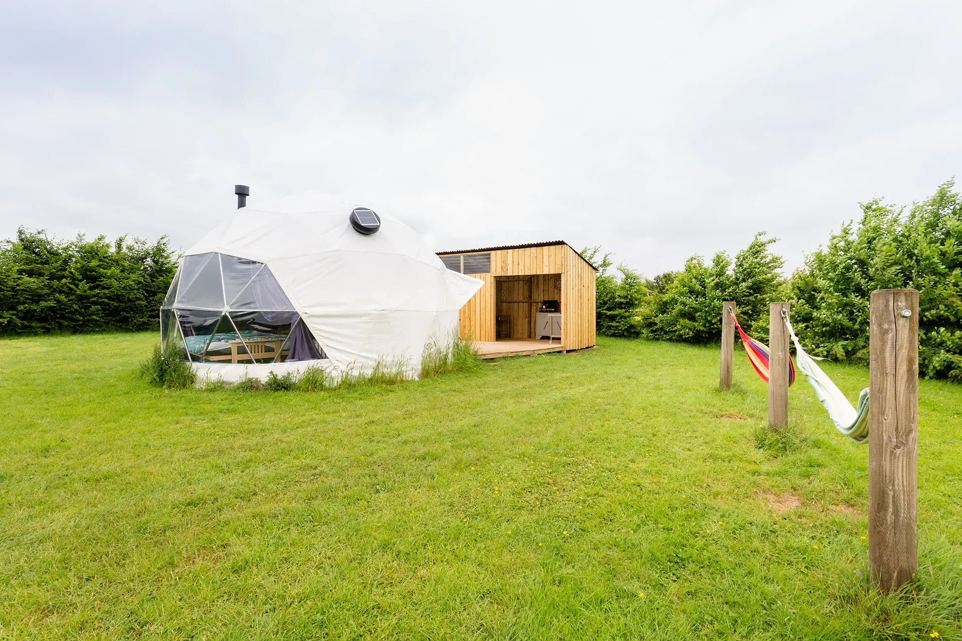 A dome tent is sitting in the middle of a grassy field.