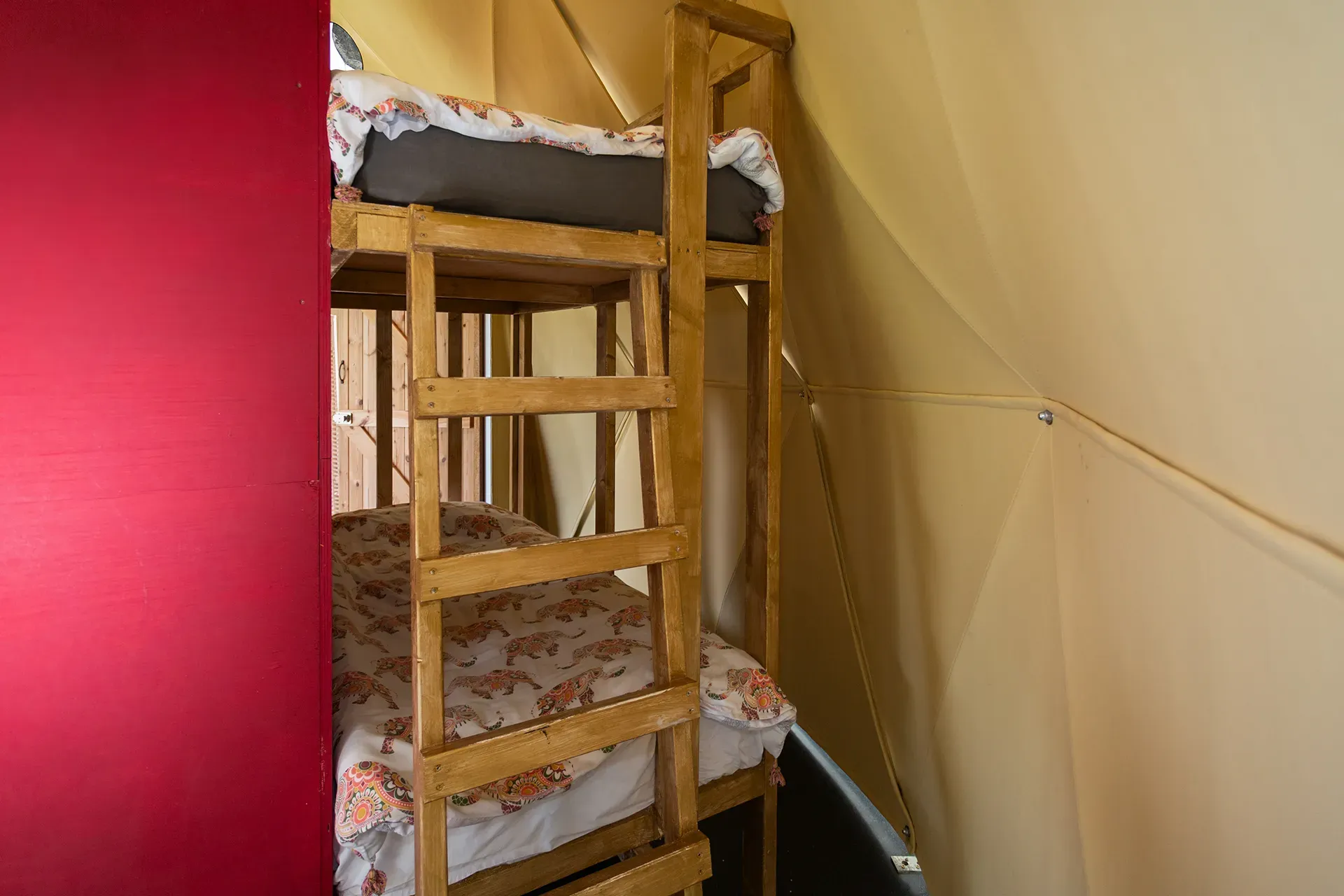 A bunk bed with a ladder in a tent.