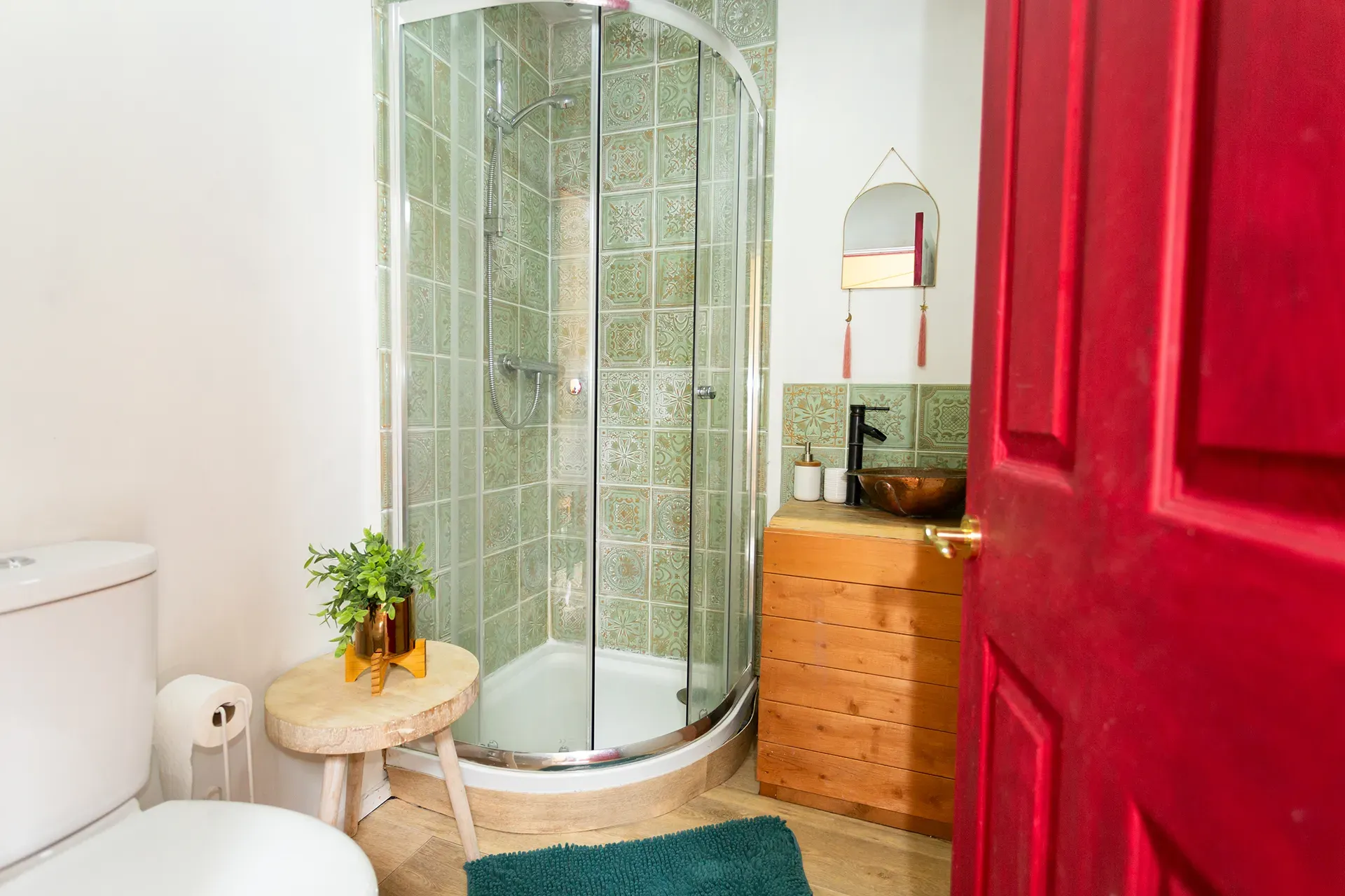 A bathroom with a toilet , sink , shower and red door.