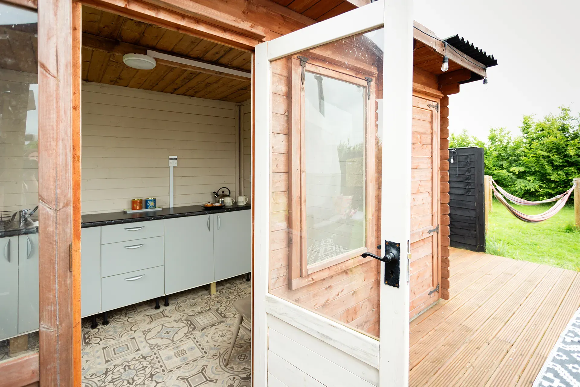 A wooden house with a kitchen and a hammock in the backyard.