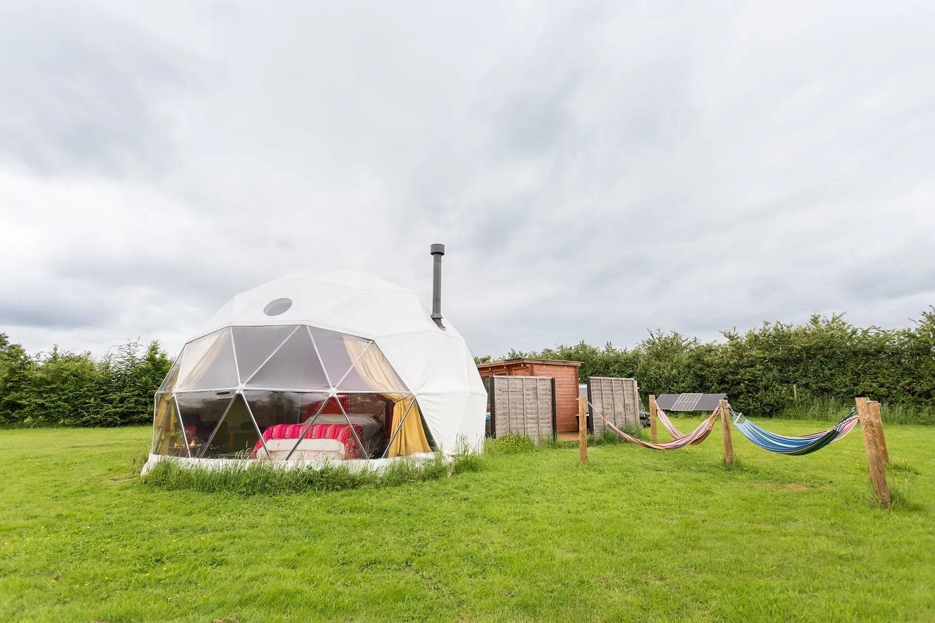 A dome tent is sitting in the middle of a grassy field.