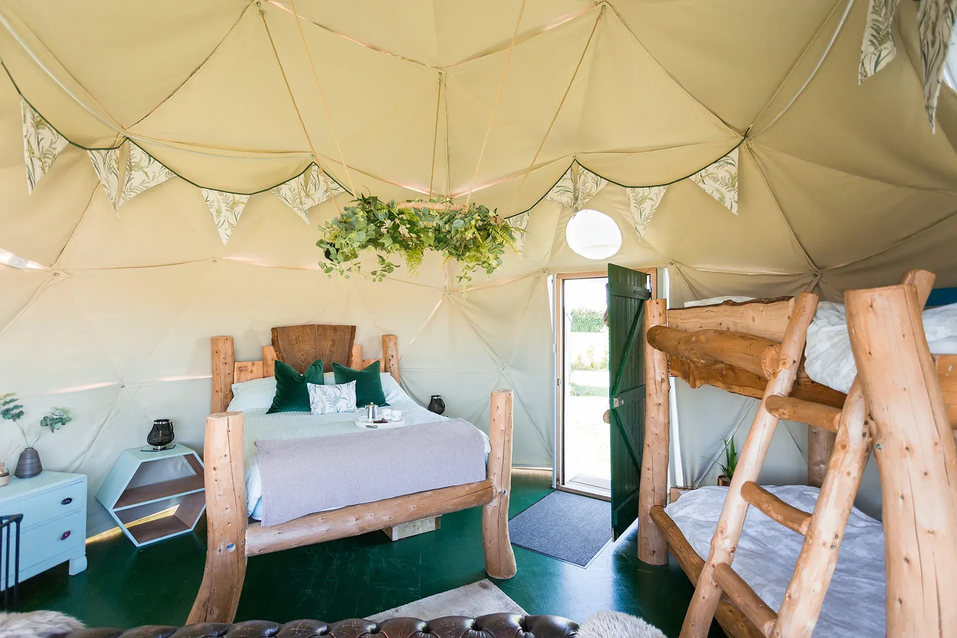 A bedroom with a bed and bunk beds in a tent.