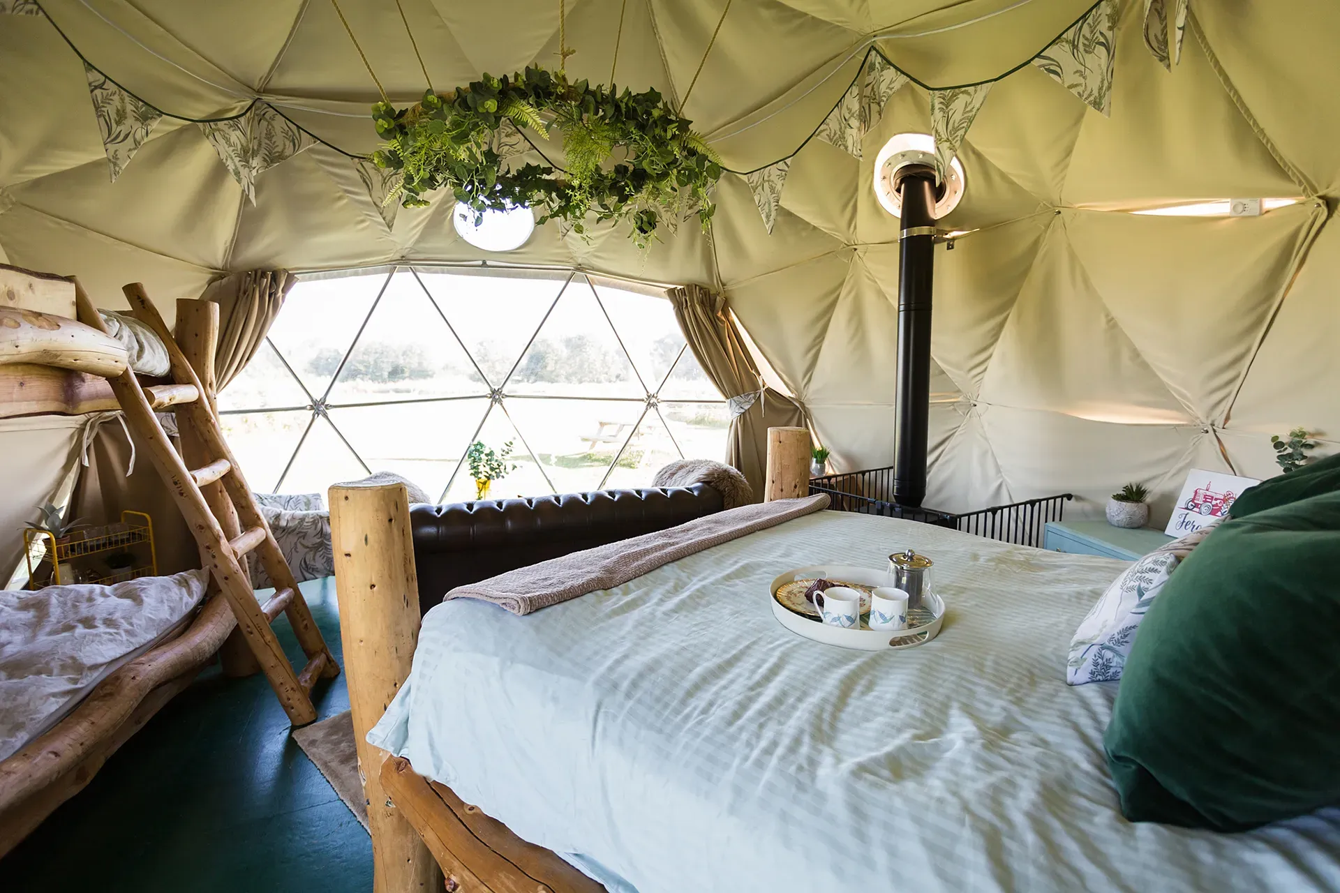 A bedroom in a dome with a bed , bunk beds , and a window.