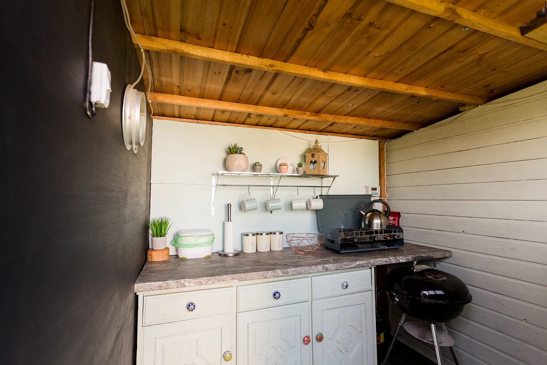 A small kitchen with a wooden ceiling and a grill.