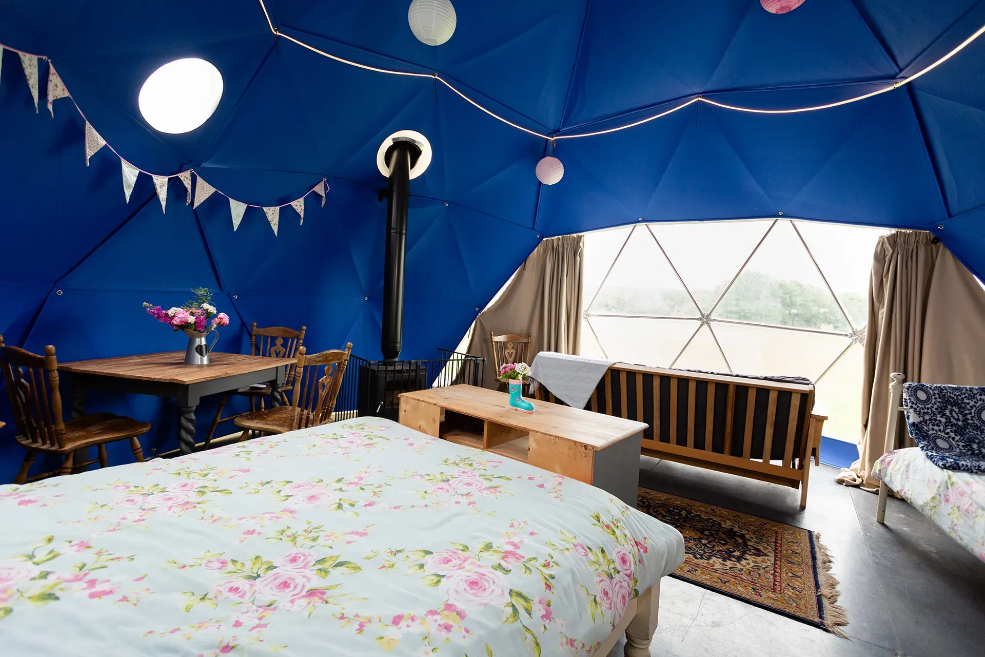 A bedroom with a bed , couch , table and chairs in a dome tent.