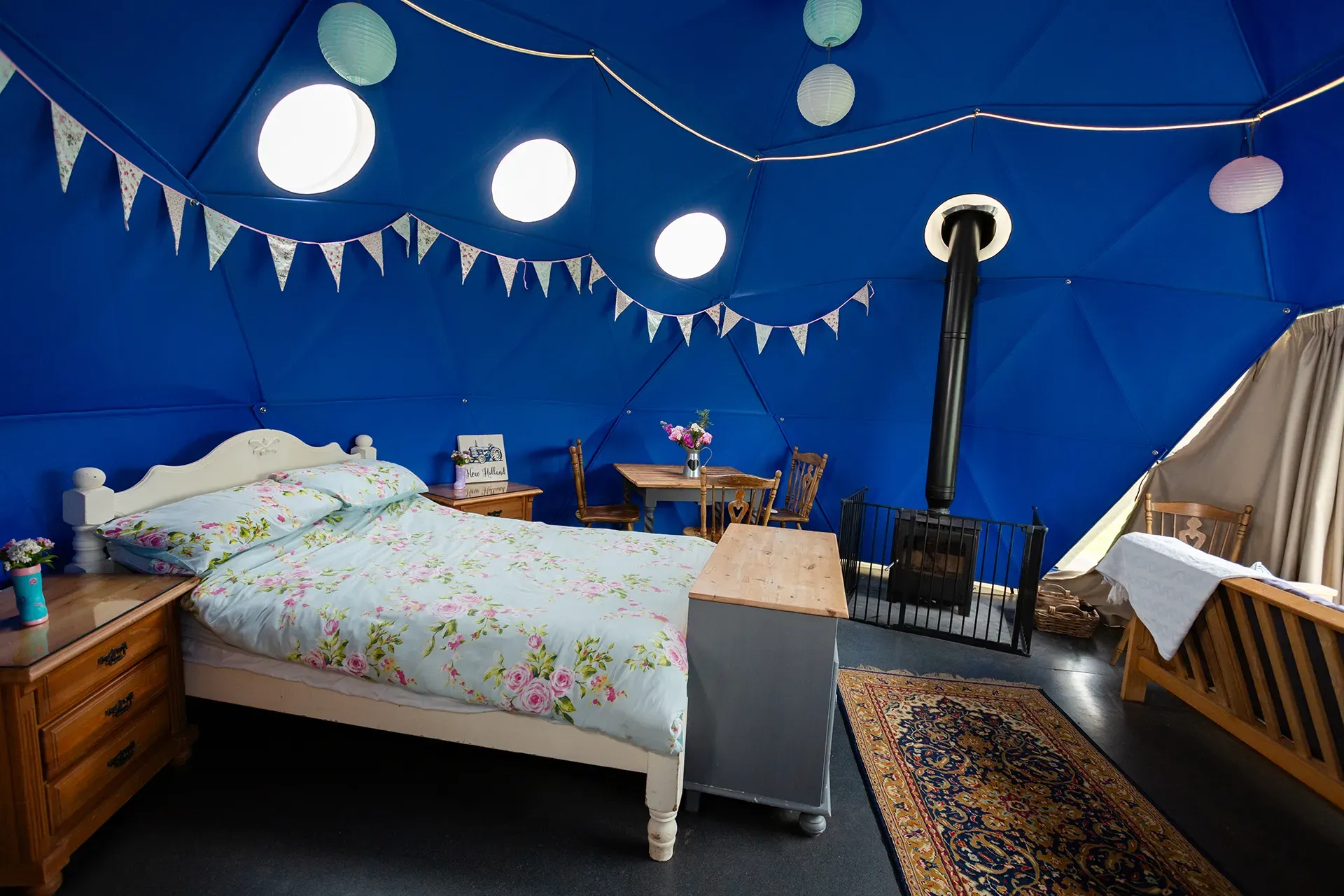 A bedroom with a bed , dresser , table and chairs in a dome.