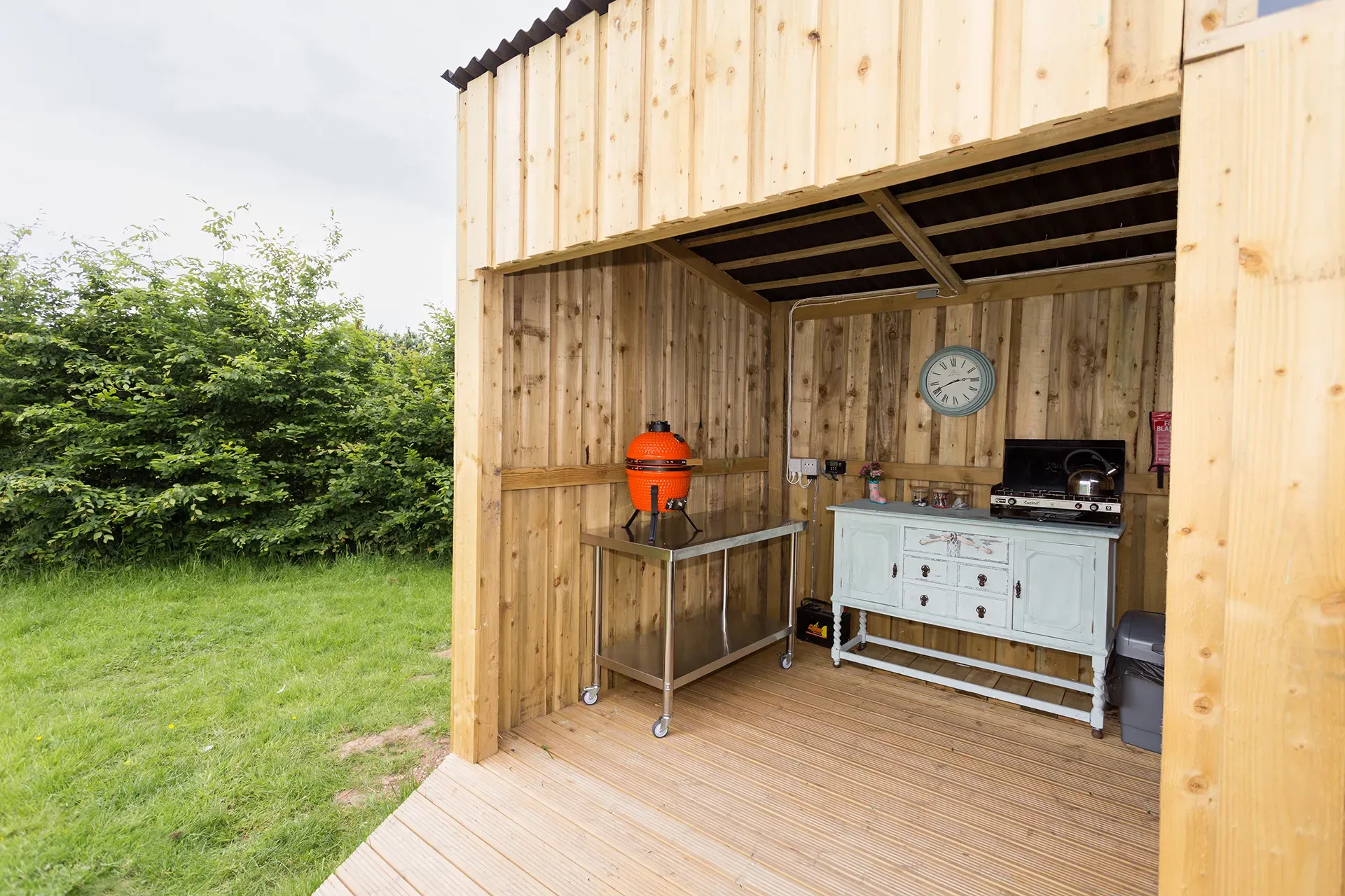 A wooden shed with a table and a grill inside of it.