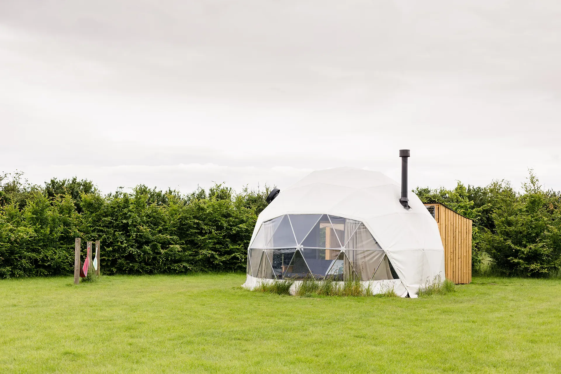 A dome tent is sitting in the middle of a grassy field.