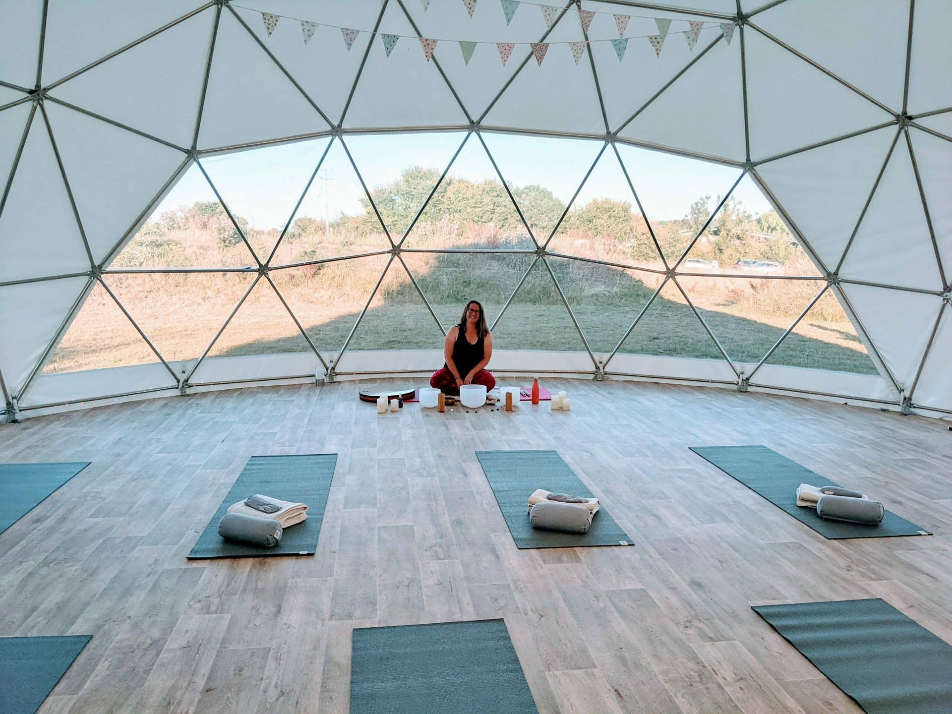 A woman is sitting on a yoga mat in a dome.