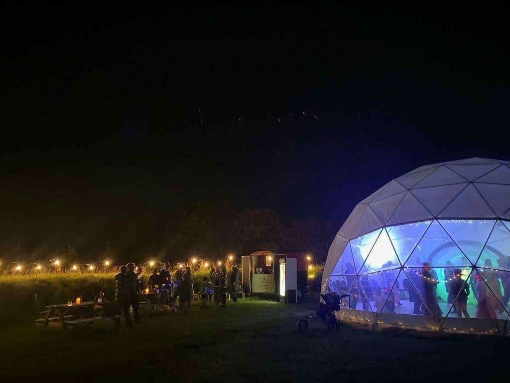 A group of people are standing in front of a dome at night.