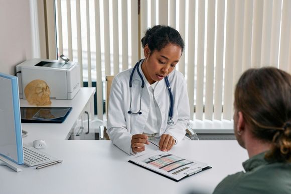 A doctor is sitting at a desk talking to a patient.