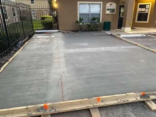 Freshly poured gray concrete slab with wooden formwork.